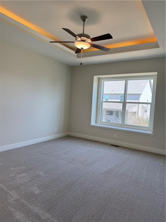 25297 W 149th Ter, Olathe, KS 66061 - carpeted empty room with a raised ceiling, baseboards, and ceiling fan