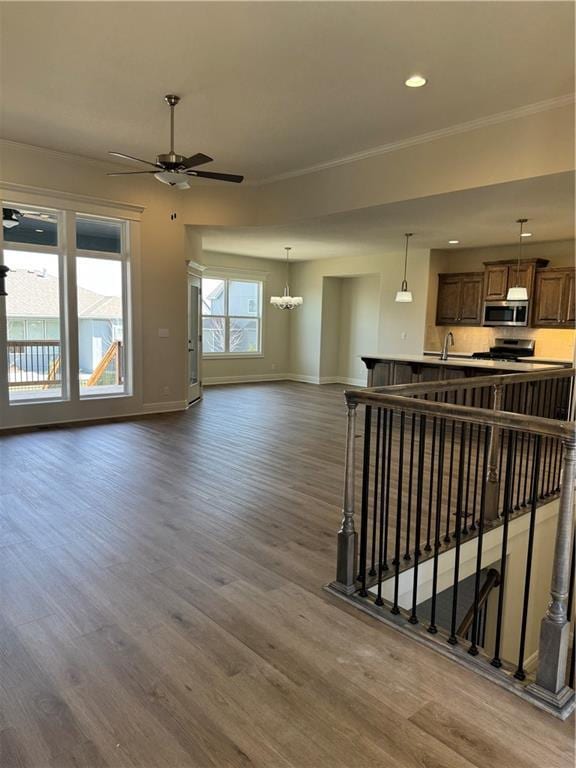 25297 W 149th Ter, Olathe, KS 66061 - unfurnished living room featuring crown molding, baseboards, a ceiling fan, dark wood-style flooring, and a chandelier