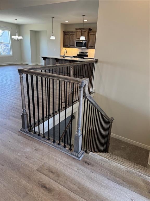 25297 W 149th Ter, Olathe, KS 66061 - stairs with wood finished floors, baseboards, and a chandelier