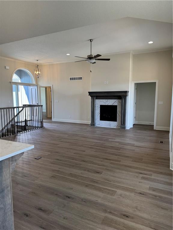 25297 W 149th Ter, Olathe, KS 66061 - unfurnished living room with baseboards, ceiling fan, a fireplace, dark wood-style floors, and vaulted ceiling
