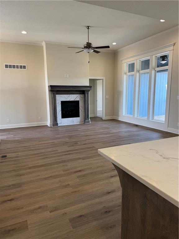 25297 W 149th Ter, Olathe, KS 66061 - unfurnished living room featuring crown molding, ceiling fan, dark wood-style flooring, baseboards, and a fireplace