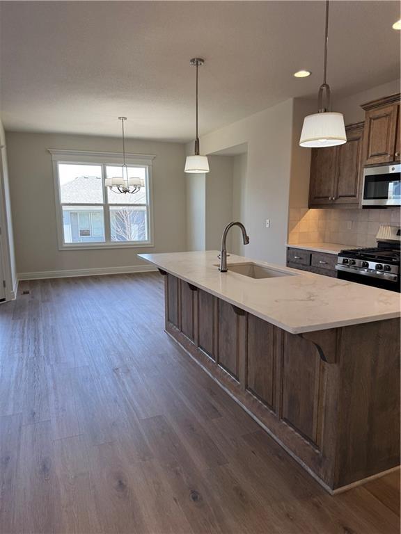 25297 W 149th Ter, Olathe, KS 66061 - kitchen with stainless steel appliances, a sink, dark wood-type flooring, a large island with sink, and baseboards