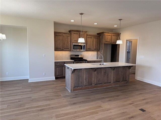 25297 W 149th Ter, Olathe, KS 66061 - kitchen with stainless steel appliances, a sink, baseboards, light countertops, and light wood finished floors