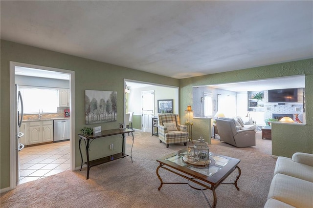 living area featuring light tile patterned floors, a stone fireplace, a healthy amount of sunlight, and light colored carpet