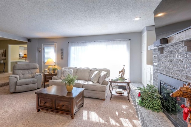 living area featuring a glass covered fireplace, light carpet, plenty of natural light, and a textured ceiling