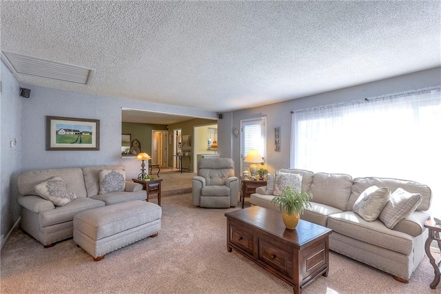 living area with a textured ceiling, visible vents, and light colored carpet