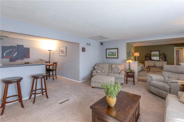 living room featuring baseboards, visible vents, a textured ceiling, and a dry bar