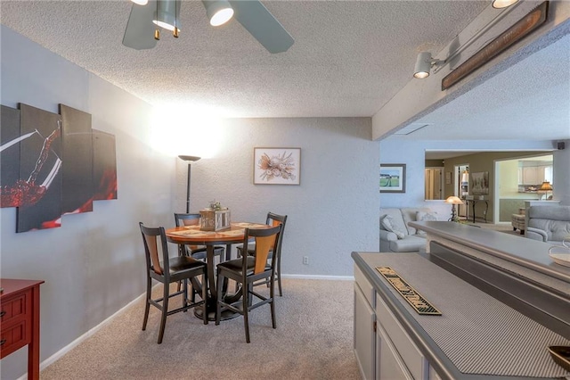 dining room featuring ceiling fan, a textured ceiling, baseboards, and light colored carpet