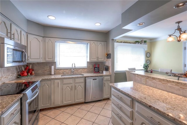 kitchen featuring light tile patterned floors, a sink, appliances with stainless steel finishes, decorative backsplash, and pendant lighting