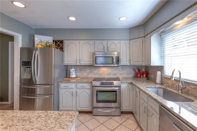 kitchen featuring light tile patterned floors, tasteful backsplash, stainless steel appliances, and a sink