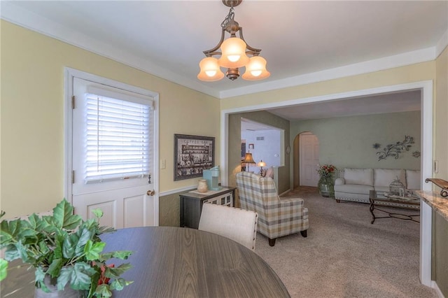 carpeted dining room featuring arched walkways and an inviting chandelier