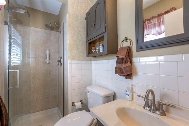 full bath with toilet, vanity, tile walls, wainscoting, and a stall shower