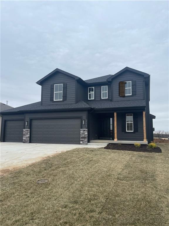 25271 W 149th Ter, Olathe, KS 66061 - view of front of property with a front yard, a garage, stone siding, covered porch, and driveway