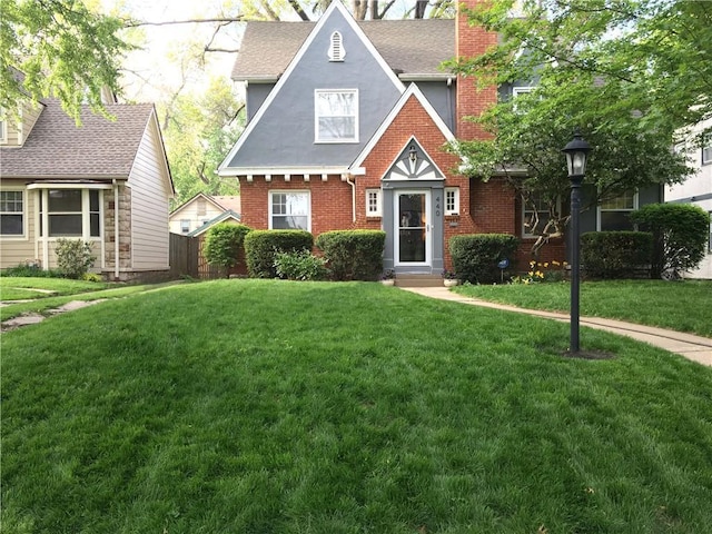 view of front of house with a front lawn, a chimney, fence, and brick siding