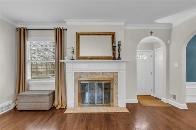 unfurnished living room featuring a tiled fireplace, visible vents, wood finished floors, and ornamental molding