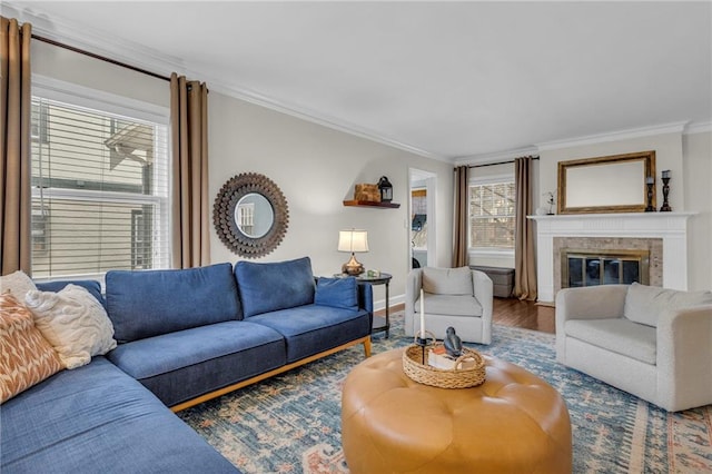 living area featuring a fireplace, baseboards, crown molding, and wood finished floors