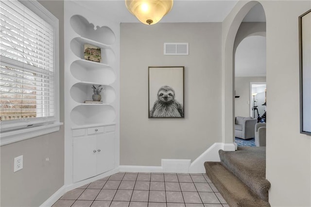 entryway featuring arched walkways, visible vents, baseboards, and light tile patterned floors