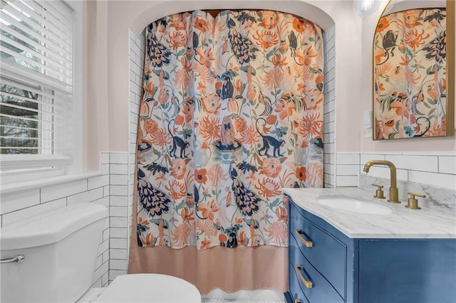 bathroom with toilet, tile walls, a wealth of natural light, and vanity