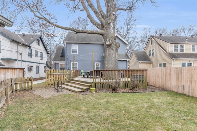 back of property with a fenced backyard, a yard, and a wooden deck