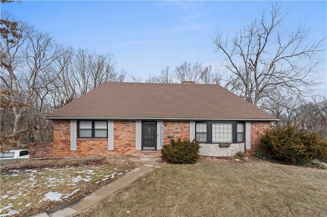 single story home featuring brick siding, a chimney, a front lawn, and roof with shingles