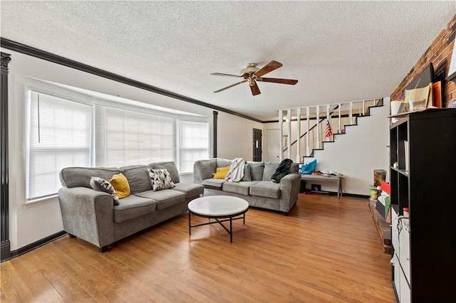 living area with stairs, a textured ceiling, light wood-type flooring, and crown molding