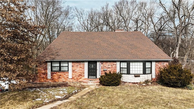 cape cod home featuring brick siding, a shingled roof, and a front yard