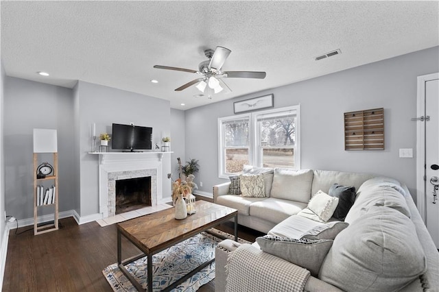 living room featuring visible vents, a textured ceiling, baseboards, and wood finished floors