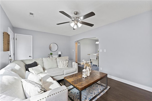 living room with arched walkways, wood finished floors, a ceiling fan, visible vents, and baseboards