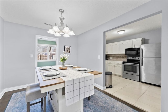 dining area featuring visible vents, baseboards, and an inviting chandelier