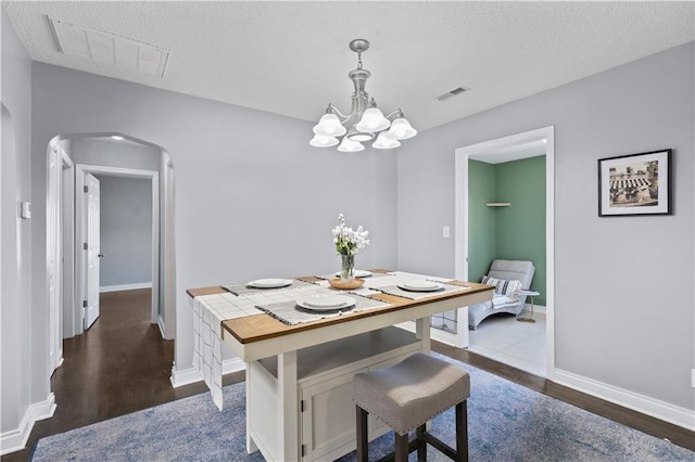 dining space with arched walkways, dark wood-type flooring, visible vents, and baseboards