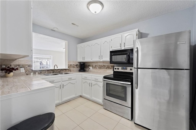 kitchen featuring visible vents, stainless steel appliances, white cabinetry, a sink, and light tile patterned flooring