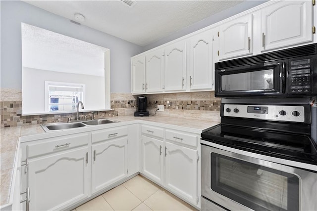 kitchen with black microwave, light tile patterned flooring, a sink, stainless steel electric range, and backsplash