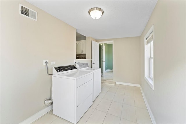 laundry room featuring light tile patterned floors, visible vents, washing machine and dryer, laundry area, and baseboards