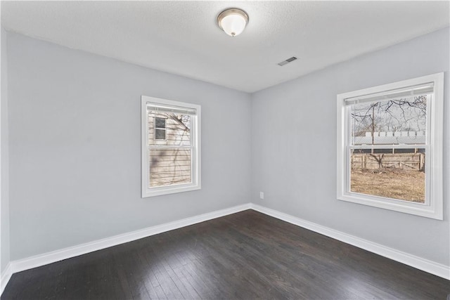 unfurnished room with baseboards, visible vents, and dark wood-style flooring