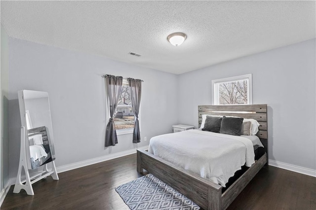 bedroom with wood finished floors, visible vents, and multiple windows