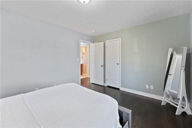 bedroom featuring a textured ceiling, baseboards, and dark wood-style flooring