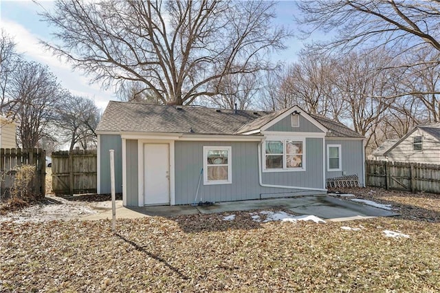 rear view of property featuring a shingled roof and fence