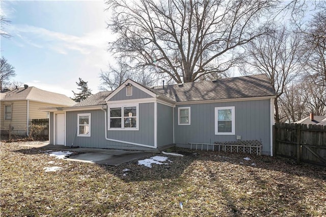 rear view of house with roof with shingles, fence, and a patio