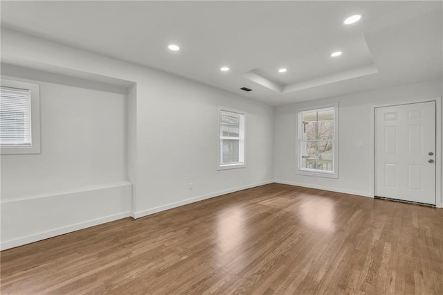 unfurnished room with hardwood / wood-style flooring and a tray ceiling