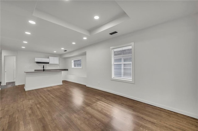 unfurnished living room featuring dark hardwood / wood-style floors and a tray ceiling