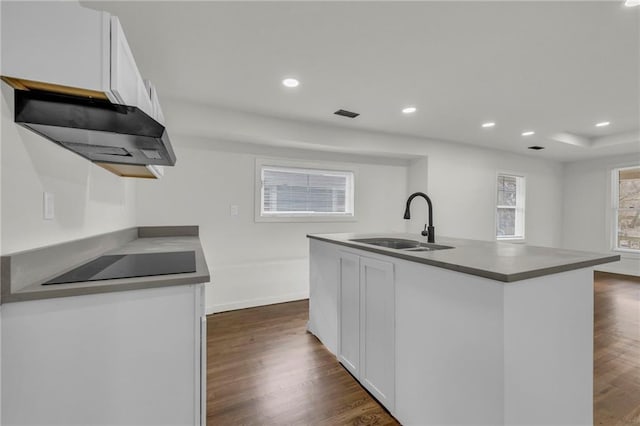 kitchen featuring sink, a kitchen island with sink, black electric stovetop, white cabinets, and dark hardwood / wood-style flooring