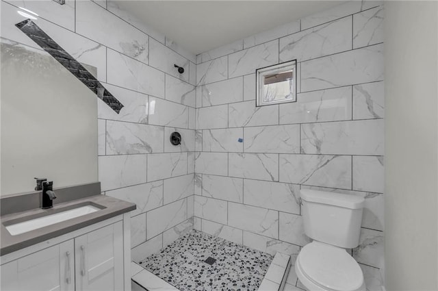 bathroom featuring vanity, a tile shower, and toilet