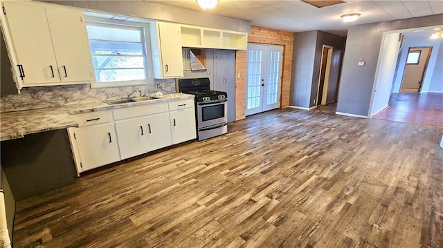 kitchen featuring sink, stainless steel gas stove, white cabinetry, light stone counters, and wood-type flooring