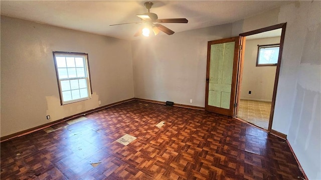 spare room featuring a wealth of natural light, dark parquet floors, and ceiling fan