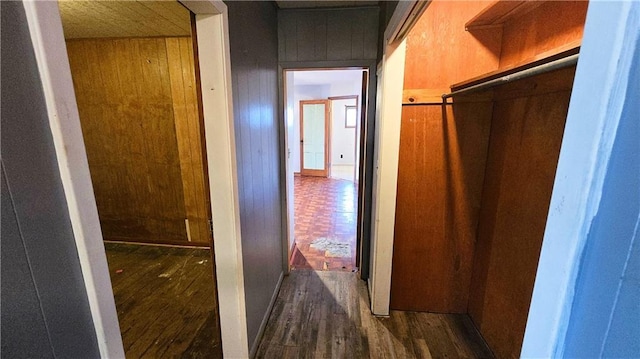 corridor featuring dark hardwood / wood-style floors and wooden walls