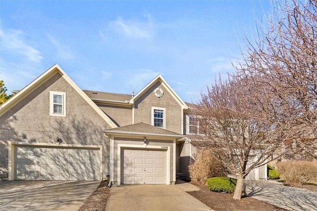 view of front of house with stucco siding, a garage, and driveway