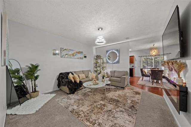 living area featuring an inviting chandelier, baseboards, carpet floors, and a textured ceiling