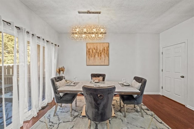 dining room with baseboards, a notable chandelier, wood finished floors, and a textured ceiling