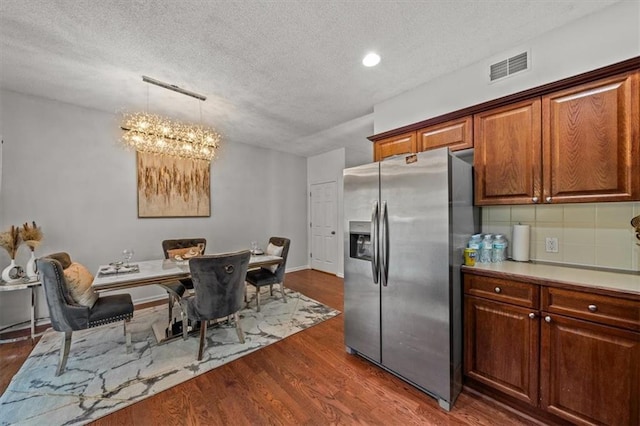 kitchen featuring visible vents, dark wood finished floors, a chandelier, decorative backsplash, and stainless steel refrigerator with ice dispenser