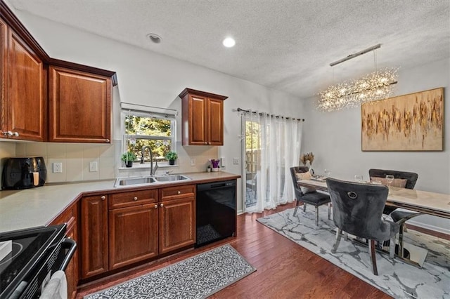 kitchen with an inviting chandelier, a sink, black appliances, dark wood-type flooring, and a wealth of natural light